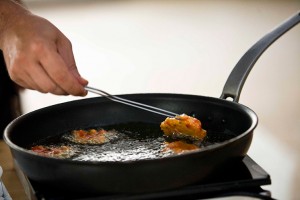 Hand frying food in pan with hot oil