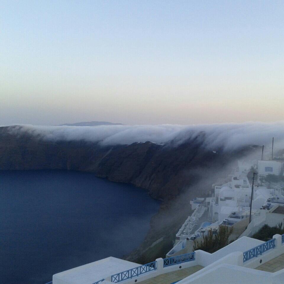 Fog rolling over coastal cliffs and white buildings