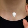 White face-shaped pendant on gold necklace