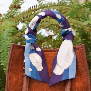 Brown handbag with patterned scarf on handle