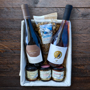 Wine and gourmet gift basket on wooden table