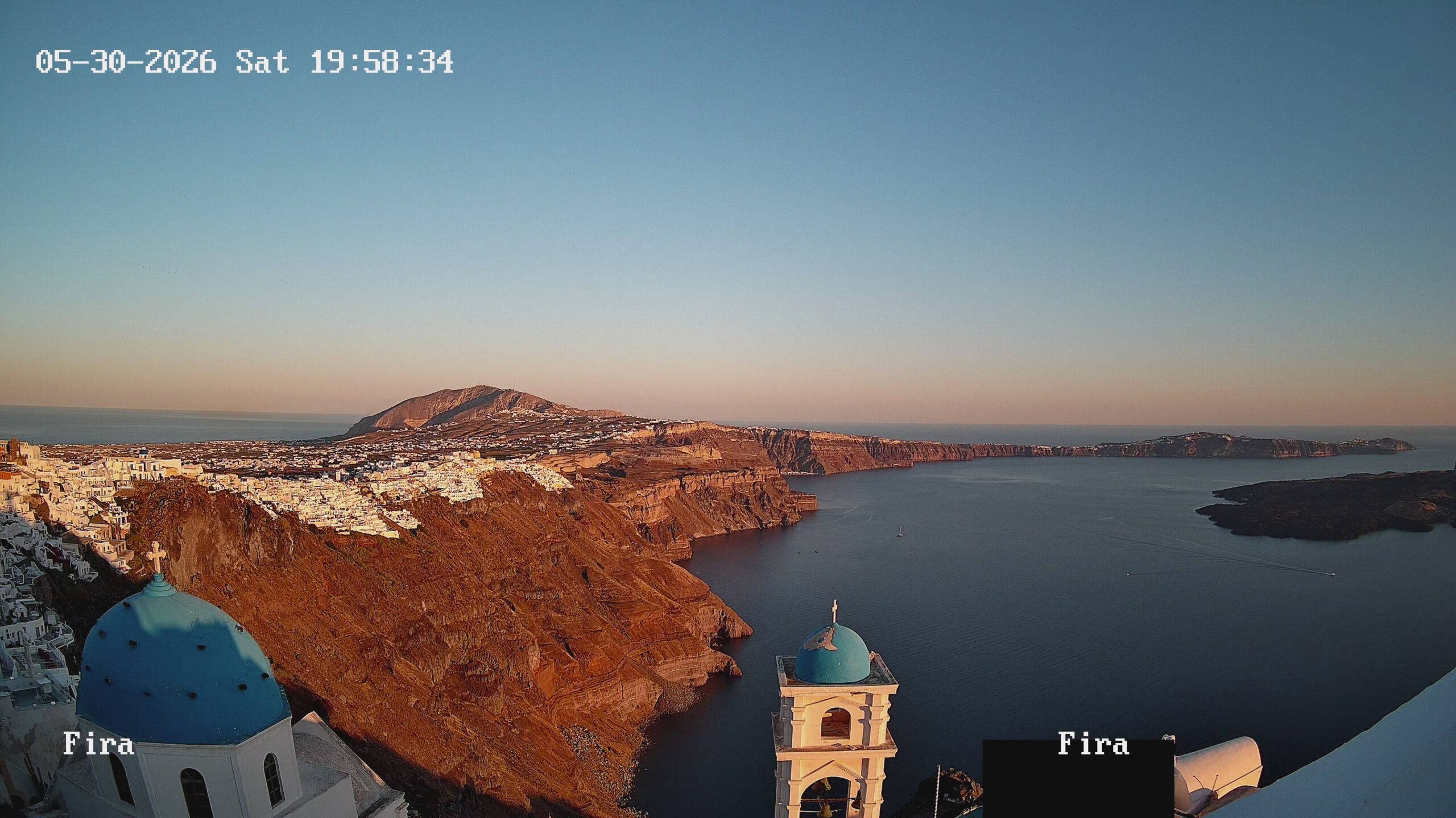 Santorini caldera at sunset with blue domes