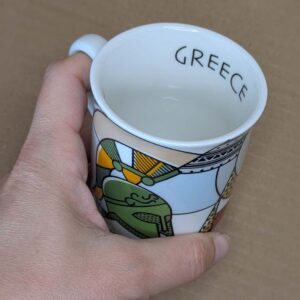 Hand holding decorative Greece souvenir mug