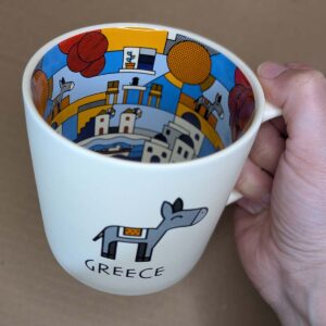 Hand holding Greece-themed illustrated ceramic mug