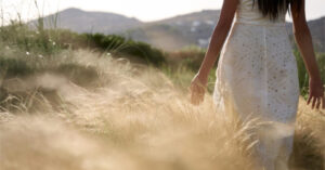 Woman in white dress walking through tall grass