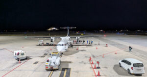 Night photo of an Aegean ATR-72 propeller aircraft that has just landed at Santorini airport