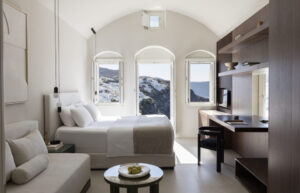 Modern bedroom with arched windows overlooking coastal cliffs