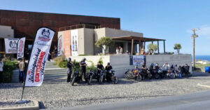 Motorcyclists gathered outside modern building near coast