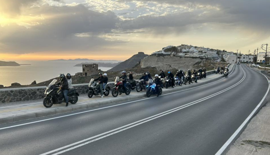 Motorcyclists lined up along coastal road at sunset