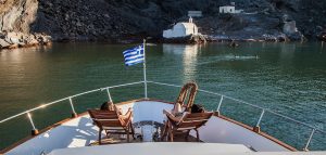 Couple relaxing on yacht near the Santorini island chapel Eptapedes