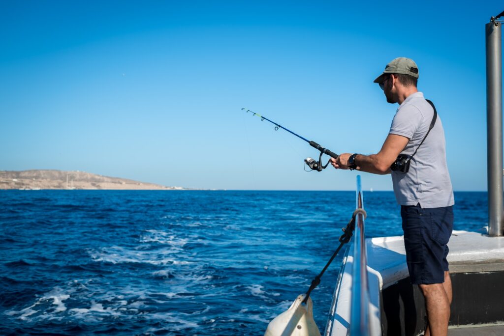 Man fishing from boat on blue ocean