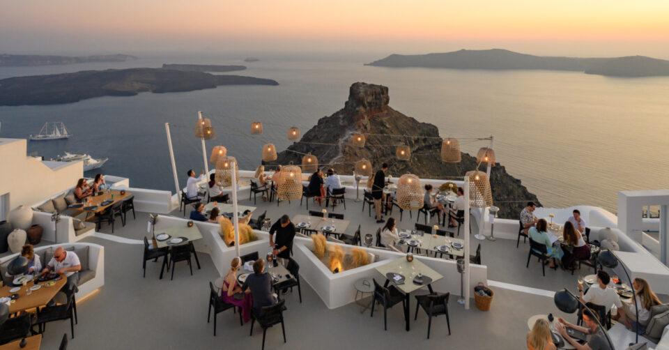 Clifftop restaurant overlooking Santorini caldera at sunset