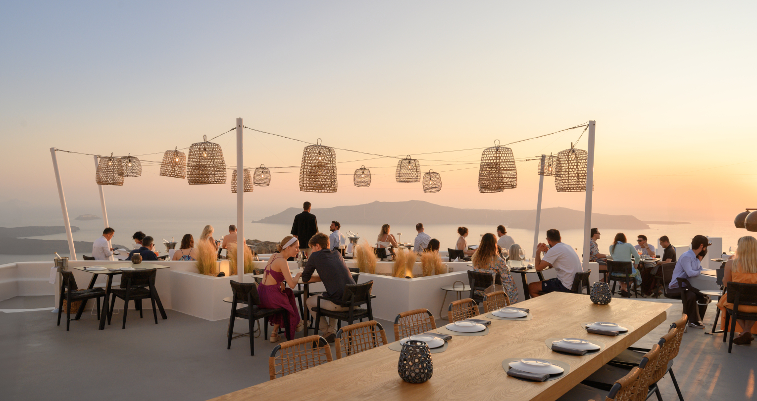 Sunset diners on a seaside terrace with woven lanterns