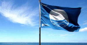 Blue Flag flying above ocean shoreline