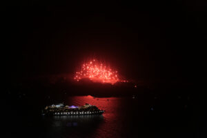 Red fireworks over cruise ship at night