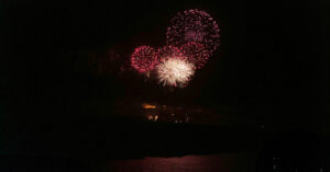 Colorful fireworks bursting over water at night