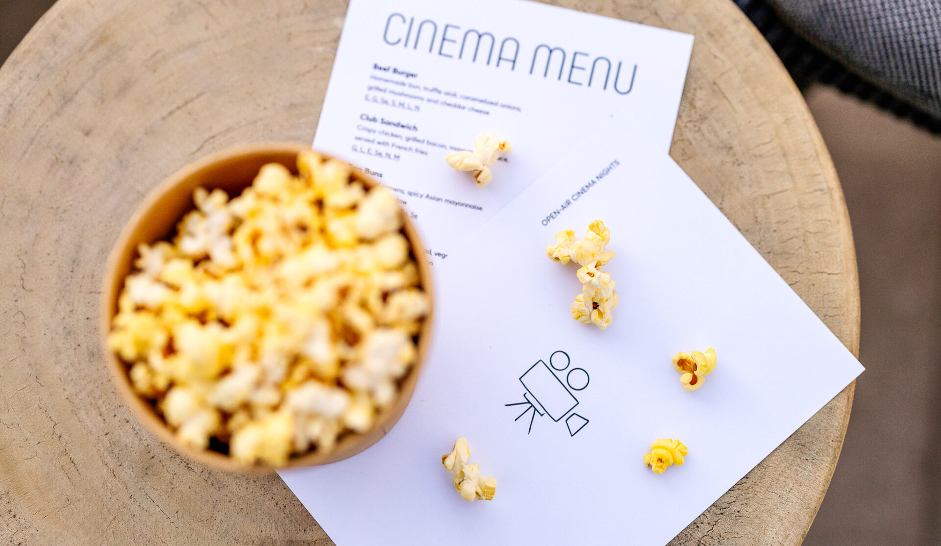 Popcorn bowl beside a cinema menu on a table