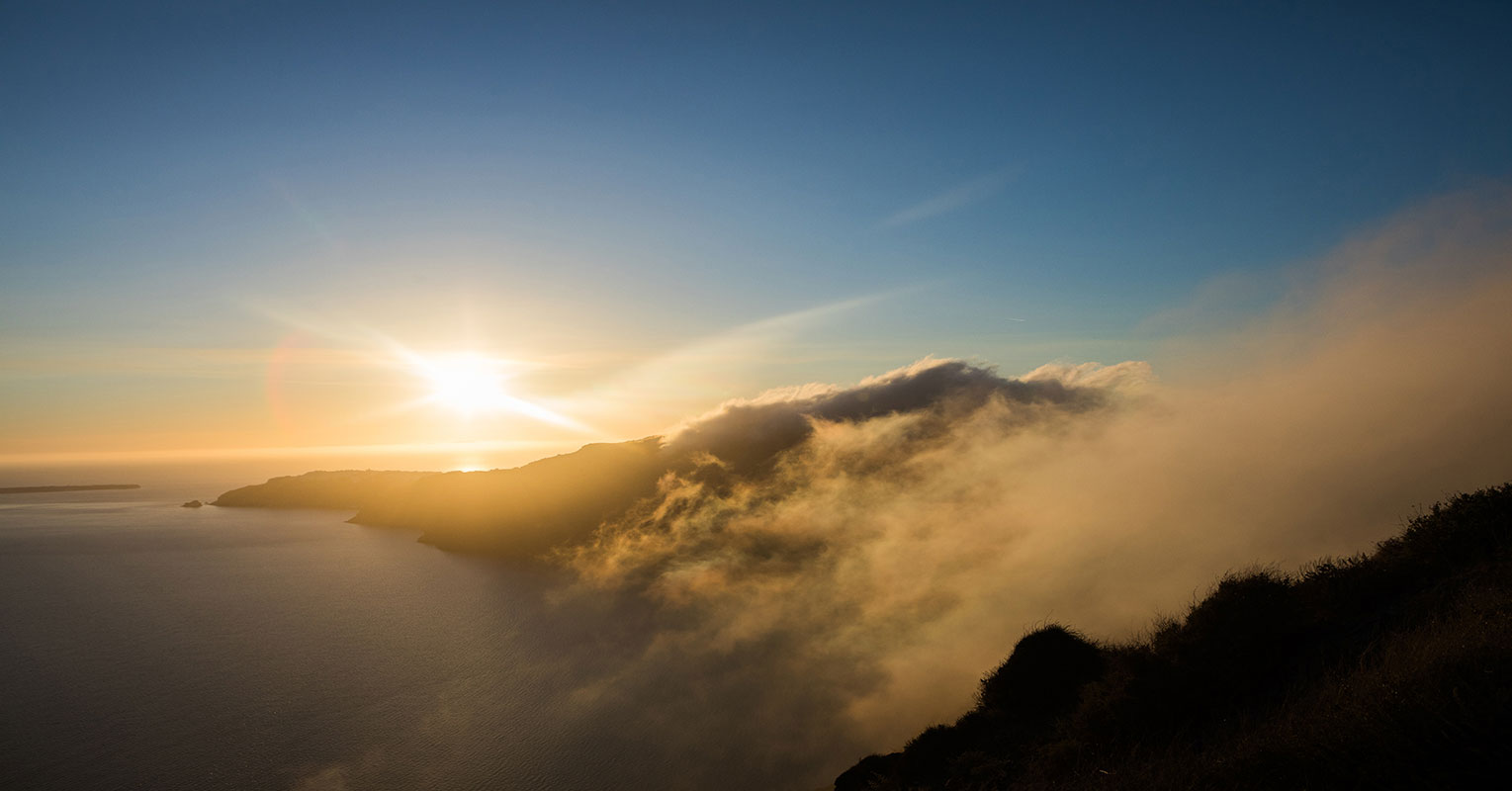 Sunset over coastal cliffs with rolling fog