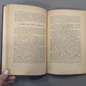 Open Greek-language book held on textured fabric