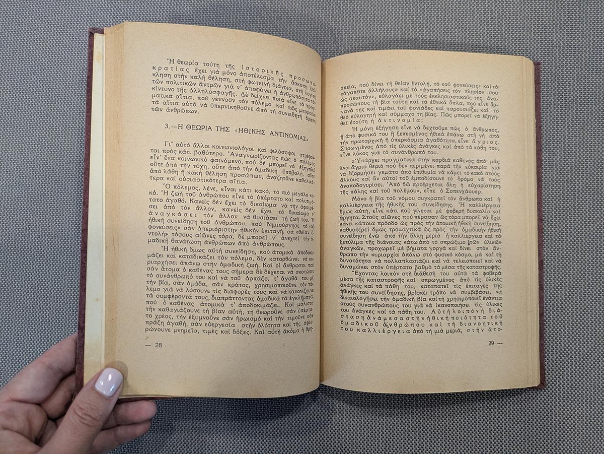 Open Greek-language book held on textured fabric