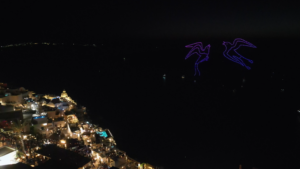 Drone light show over coastal town at night